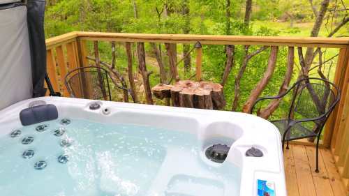 A hot tub on a wooden deck surrounded by trees, with two chairs and a small table nearby.