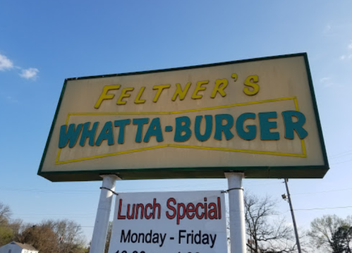 Sign for Feltner's Whata-Burger featuring lunch specials, set against a clear blue sky.