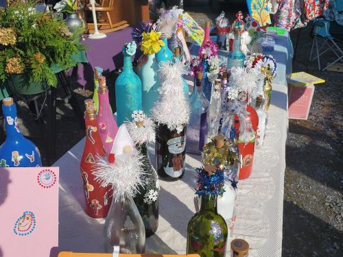 A colorful display of decorated bottles with stickers and festive embellishments at a market.