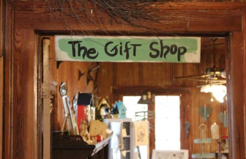 Sign for "The Gift Shop" hanging in a rustic wooden entrance with various items visible inside.