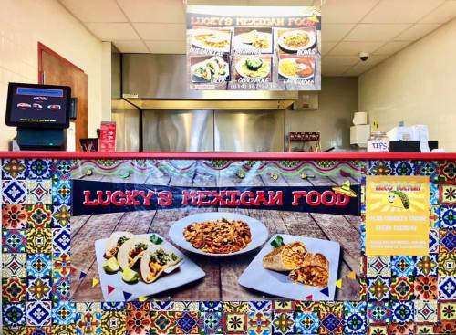 Colorful restaurant counter featuring "Lucky's Mexican Food" sign, with vibrant tiles and images of tacos and enchiladas.