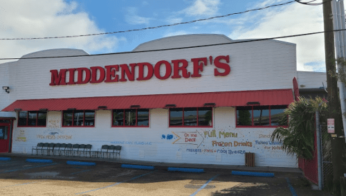 Exterior of Middendorf's restaurant with a red awning, featuring colorful signage and outdoor seating.