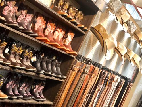 A display of cowboy boots, hats, and leather belts in a store.