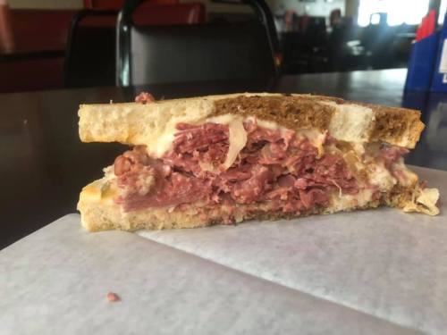 A close-up of a stacked sandwich with layers of meat and cheese, served on toasted bread.