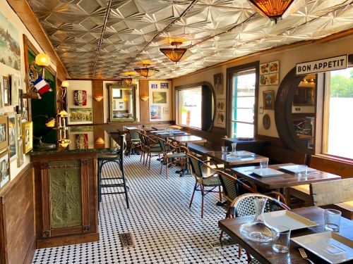 Cozy restaurant interior with wooden tables, patterned floor, vintage decor, and warm lighting.