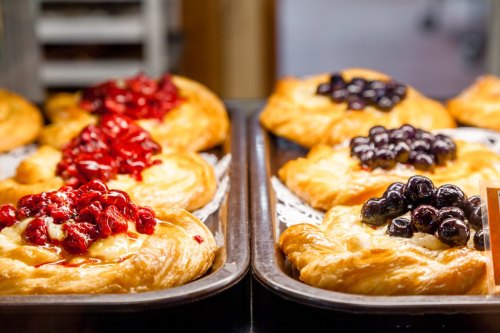 Two trays of pastries topped with red and black fruit, showcasing a golden-brown crust and creamy filling.