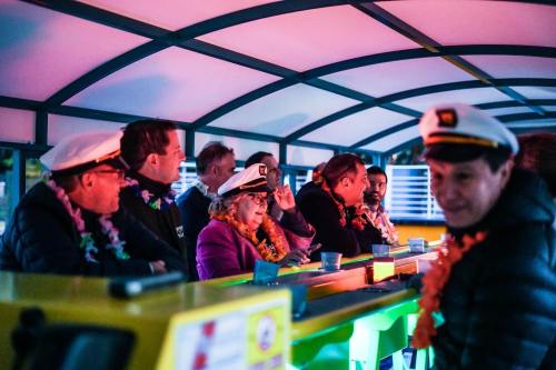 A group of people in captain hats sitting at a colorful bar, enjoying a festive atmosphere with leis around their necks.