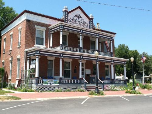 Historic brick hotel with a decorative facade, porch, and American flags, surrounded by greenery and flowers.
