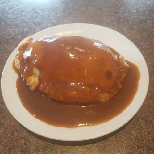 A plate with a large, golden-brown pastry covered in rich brown gravy.