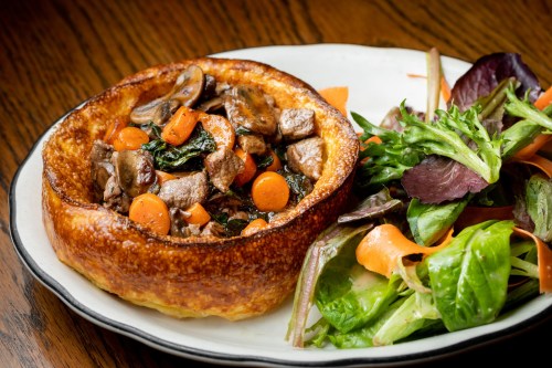 A savory meat pie filled with vegetables, served alongside a fresh mixed green salad.