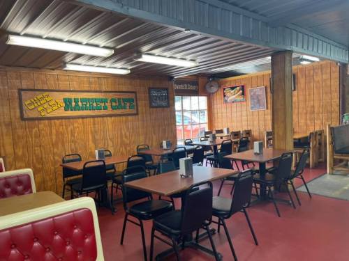 Interior of a cozy café with wooden walls, tables, and red booths, featuring a warm, inviting atmosphere.