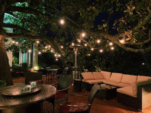 Cozy outdoor seating area at night, illuminated by string lights, with a patio heater and lush greenery.