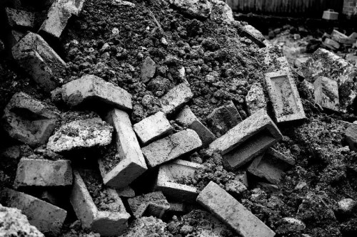 A pile of broken bricks and dirt, captured in black and white, creating a textured, rugged landscape.