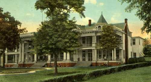 A vintage postcard of a large, elegant house surrounded by trees and a manicured lawn.