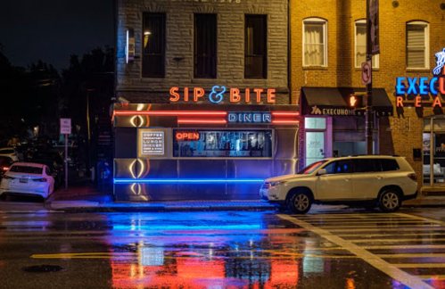 A diner named "Sip & Bite" illuminated at night, with neon lights reflecting on wet pavement.