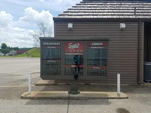 Menu board outside a restaurant displaying breakfast and lunch options, including sandwiches, sides, and drinks.
