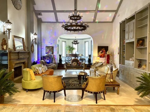 A spacious, elegantly decorated living room with colorful lighting, plush seating, and artistic decor.