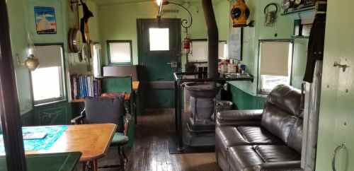 Interior of a cozy room with green walls, a table, chairs, a sofa, and a door leading outside.