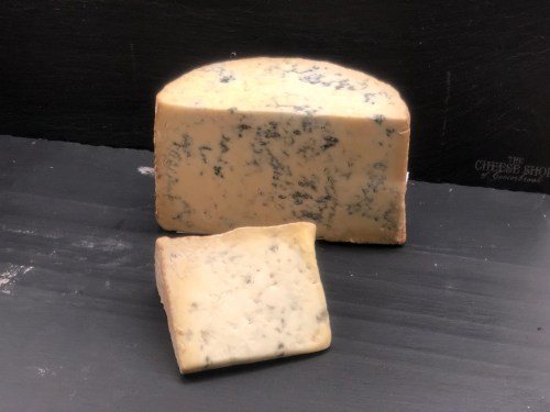 A wedge of blue cheese with a slice cut out, resting on a dark surface.