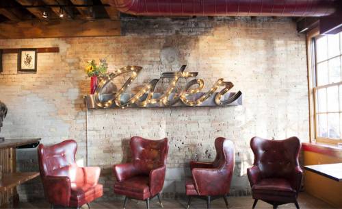 Cozy interior featuring red leather chairs and a decorative "Aster" sign against a brick wall.