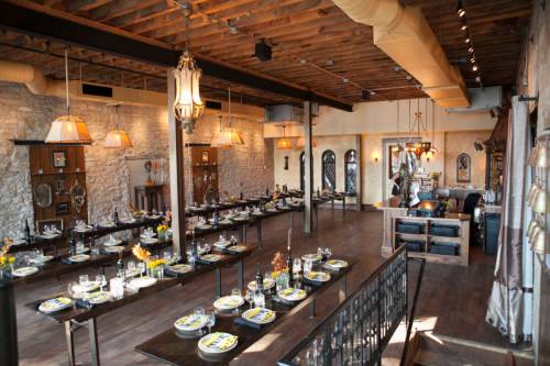 Elegant restaurant interior with wooden beams, stone walls, and tables set for dining, featuring warm lighting and decor.