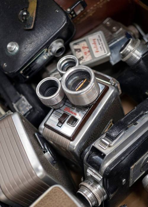 A collection of vintage cameras piled together, showcasing various designs and lenses.