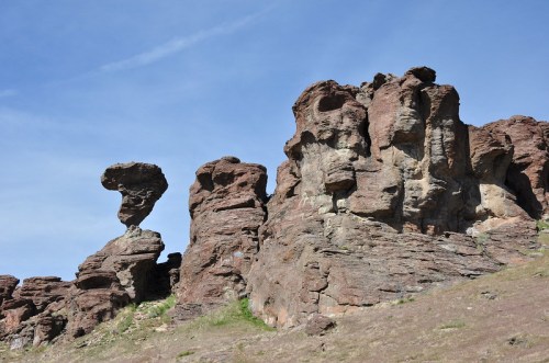 Rock formations with unique shapes against a clear blue sky, featuring a prominent balancing rock on the left.