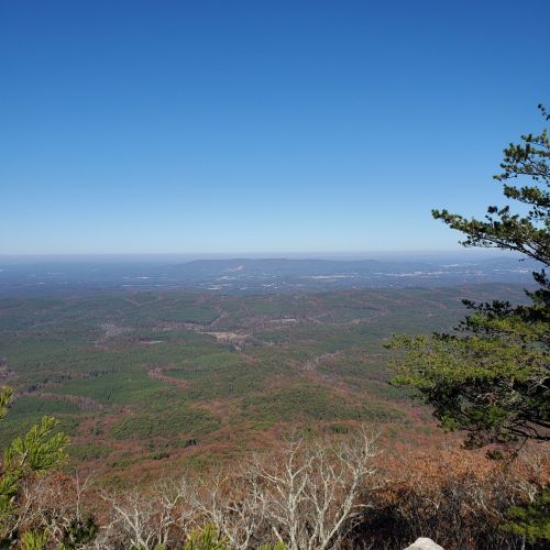 A panoramic view of rolling green hills and distant mountains under a clear blue sky.