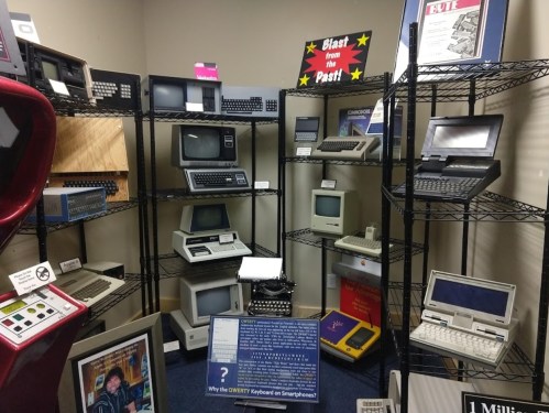 A display of vintage computers and keyboards in a museum setting, showcasing technology from the past.
