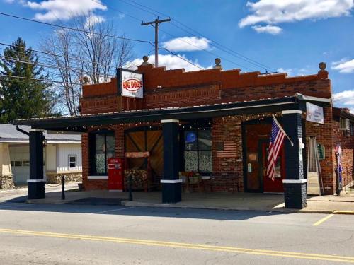 A brick building with a sign reading "Big D's," featuring an American flag and outdoor seating under a canopy.