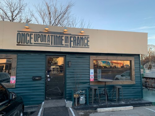 Exterior of a restaurant named "Once Upon a Time in France," featuring a blue wooden facade and outdoor seating.