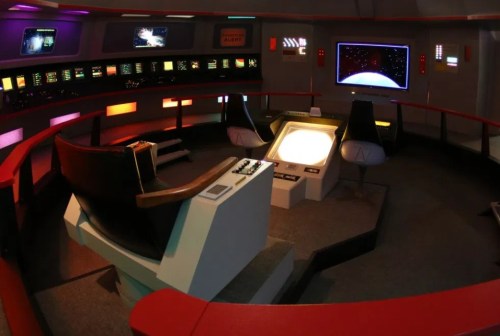 Futuristic spaceship cockpit with control panels, screens, and seating, resembling a sci-fi setting.