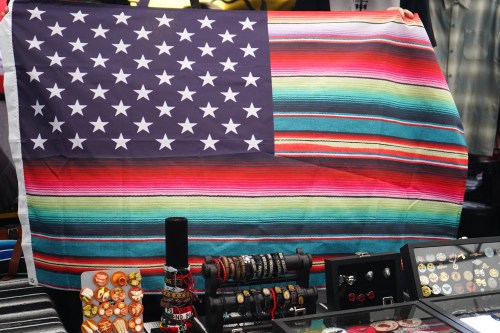 A colorful striped blanket draped over a table, featuring a blue and white star American flag design.