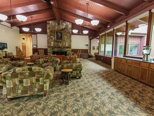 Cozy lounge area with patterned sofas, a stone fireplace, large windows, and wooden accents.