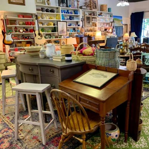 A cozy vintage shop interior filled with furniture, decor, and musical instruments, featuring a warm, inviting atmosphere.