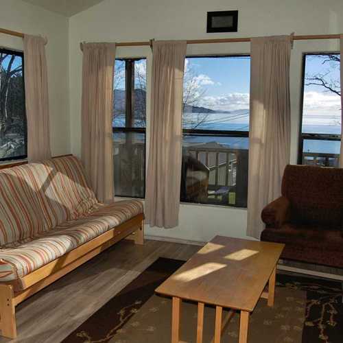 Cozy living room with a striped sofa, wooden coffee table, and large windows showcasing a scenic view.