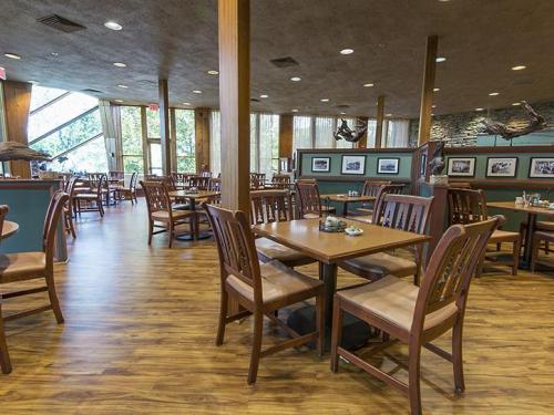 Interior of a restaurant featuring wooden tables and chairs, large windows, and a warm, inviting atmosphere.