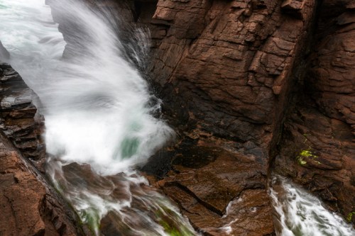 A rushing stream flows over rocky terrain, creating a dynamic contrast between water and stone.