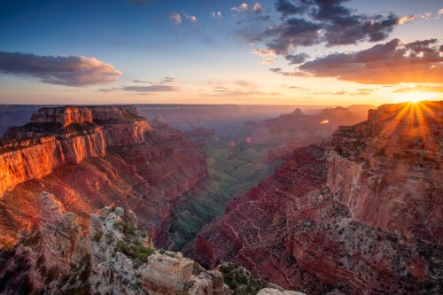 A stunning sunset over the Grand Canyon, highlighting the layered rock formations and vibrant colors of the landscape.