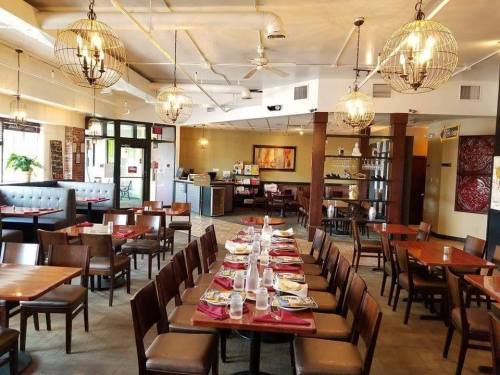 Interior of a restaurant featuring wooden tables, chairs, and decorative lighting, with a welcoming atmosphere.