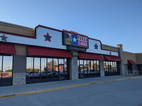 Exterior of a restaurant named "Texas T-Bone," featuring a red and white color scheme and large windows. Sign indicates it's open.