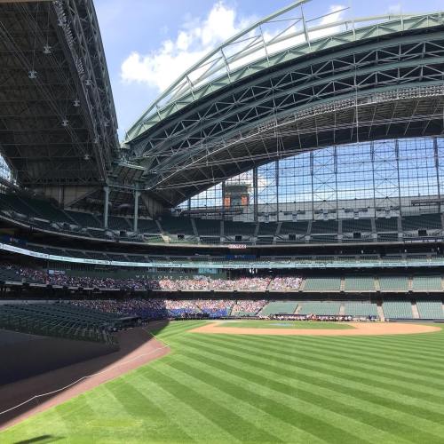 A spacious baseball stadium with a retractable roof, featuring green grass and a crowd in the stands.