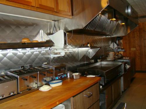 A commercial kitchen with stainless steel appliances, including toasters, a griddle, and wooden countertops.