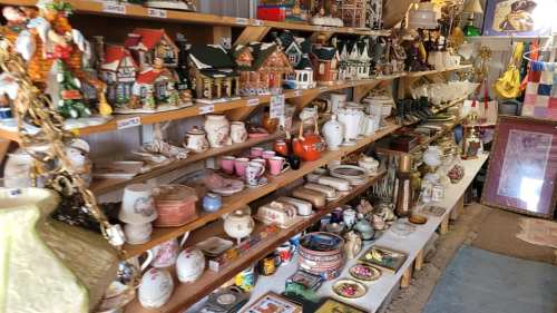 A display of various vintage items and collectibles on shelves, including teapots, figurines, and decorative plates.