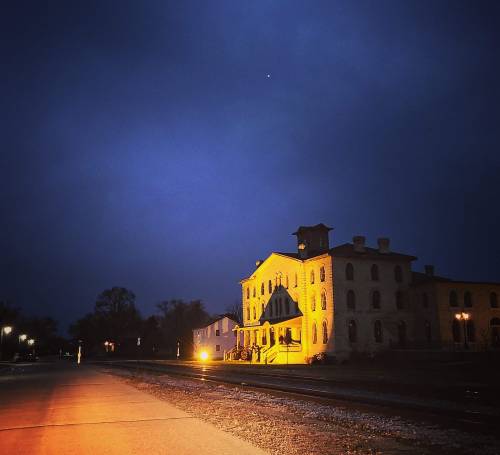 A historic building illuminated at night, with a dark blue sky and a hint of light from a distant star.
