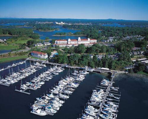 Aerial view of a marina filled with boats, surrounded by lush greenery and a large hotel in the background.