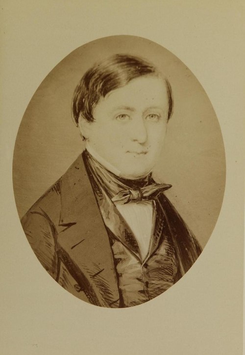 A vintage portrait of a young man in a formal suit with a bow tie, set in an oval frame.