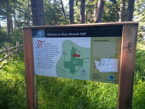Sign welcoming visitors to Mima Mounds Natural Area Preserve, featuring a map and information about the site.