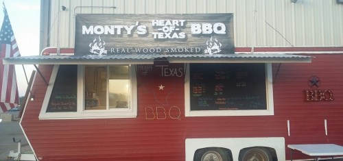 A red food truck with a sign reading "Monty's Heart of Texas BBQ" and a menu displayed on the side.