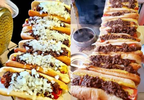 A close-up of two trays of hot dogs topped with chopped onions and chili, steaming and ready to serve.